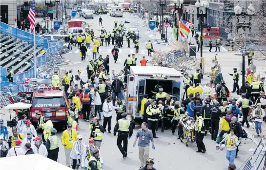  ?? CHARLES KRUPA/ AP PHOTO ?? Medical workers aid injured people (above and below) at the finish line of the 2013 Boston Marathon. Crowd-control officials tore down temporary fences to reach the wounded.