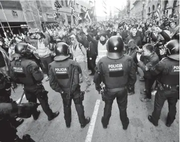  ??  ?? Riot police stand guard as people gather to protest against weekly cabinet meeting in Barcelona. — Reuters photo