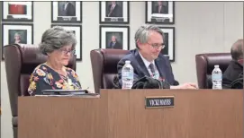  ?? / Kevin Myrick ?? Top: Bernard Morgan, the new chair of the Polk County Board of Education, shakes hands with outgoing chair Tommy Sanders as they trade seats on Tuesday night, January 8, 2019 during the opening session of the year. Above: New school board members Vicki Mayes and Britt Madden Jr. got down to work during their first session.