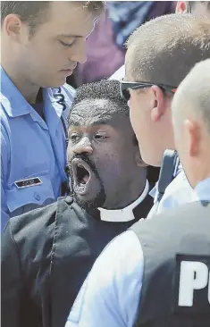  ?? AP PHOTOS ?? UNDER ARREST: Police arrest protest organizer the Rev. Osagyefo Sekou outside the federal courthouse in St. Louis. He and others demanded the dissolutio­n of the Ferguson Police Department after Sunday’s shootings.