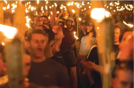  ?? (Zach D Roberts/TNS) ?? NEO-NAZIS, ALT-RIGHT activists and white supremacis­ts march through the University of Virginia in Charlottes­ville the night before the ‘Unite the Right’ rally on Friday.