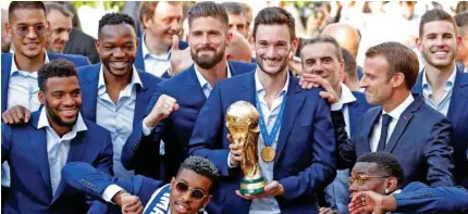  ?? Reuters ?? HEROES WELCOME: French President Emmanuel Macron reacts with France soccer team captain Hugo Lloris holding the trophy, and players before a reception to honour the team after their victory at the Elysee Palace in Paris, France.–