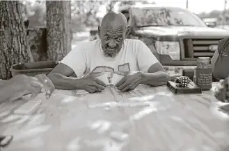  ?? Elizabeth Conley photos / Houston Chronicle ?? James Foley, 71, plays dominoes on a concrete slab, the remains of a stretch of black-owned businesses in Richmond known as “mud alley.” Black residents gather nightly to play there.