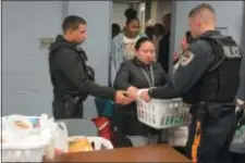  ?? PHOTOS BY JOHN BERRY — THE TRENTONIAN ?? Trenton police officers Walter DeLeon, left, and Steven Garzio, right, hand out baskets of groceries to Trenton families during the department’s annual Thanksgivi­ng meal giveaway.
