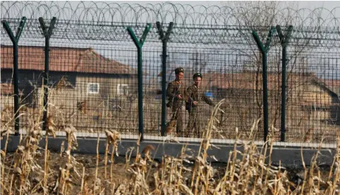  ?? (Damir Sagolj/Reuters) ?? NORTH KOREAN soldiers patrol behind a border fence near the North Korean town of Sinuiju last week.