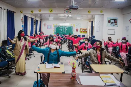  ?? The Associated Press ?? Students mime a hug after schools reopened Monday in New Delhi, India. Delhi on Monday opened schools for Grade 10 to 12 students after a gap of more than nine months.