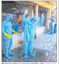  ?? (AP/Rafiq Maqbool) ?? Municipal workers in personal protective suits sanitize themselves after cremating a covid-19 victim in Vasai, outskirts of Mumbai, India.