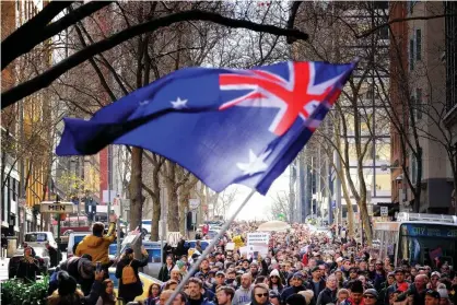  ?? Photograph: Luis Ascui/AAP ?? Protesters wave an Australian flag during an anti-lockdown rally in Melbourne on Saturday.