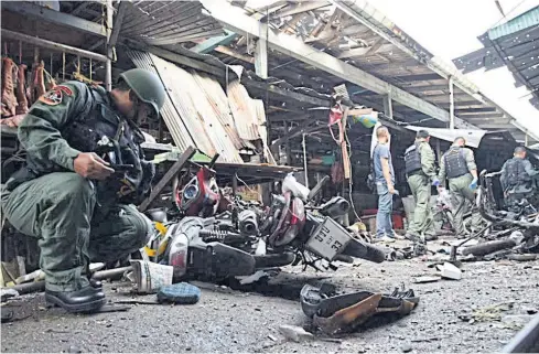  ?? MUHAMAD AYUB PATHAN ?? A security officer inspects the scene where a bomb went off at Pimolchai fresh food market in Yala this January.