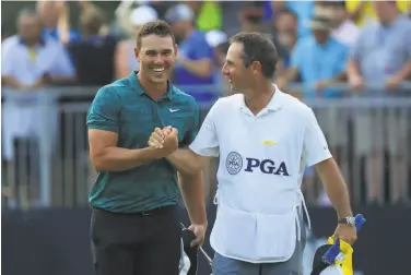  ?? Sam Greenwood / Getty Images ?? Brooks Koepka celebrates with caddie Ricky Elliott after winning the PGA Championsh­ip at Bellerive Country Club in St. Louis. Koepka shot a 4-under-par 66 to finish 16-under for a two-shot victory.