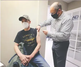  ?? DAN JANISSE ?? Chris Laramie, 56, receives a dose of the Astrazenec­a vaccine on Tuesday from pharmacist Tim Brady at the Brady's Drug Store in Belle River. Many area pharmacies have few or no vaccine doses available.