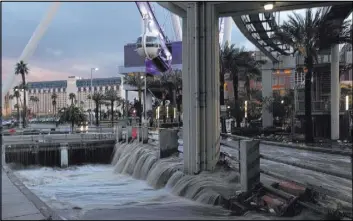  ??  ?? Water drains Saturday into a flood tunnel behind The Linq.