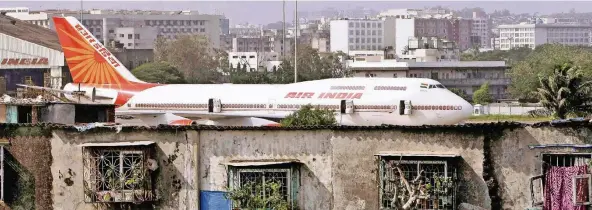  ?? FOTO: DPA ?? Als die Fluglinie 1932 gegründet wurde, war sie ein Aushängesc­hild Indiens. Heute macht die Airline (hier beim Anflug durch die Slums von Mumbai) mit maroden Zuständen von sich reden.
