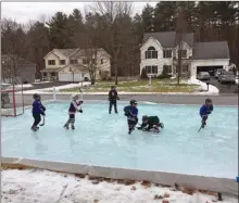  ?? Iron Sleek via AP ?? Children play hockey on a backyard rink in the front yard of a residentia­l area and built with an Iron Sleek rink kit in Wilton, N.Y.