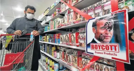  ?? BILAWAL ARBAB / EFE ?? BOICOT A FRANCIA. Un hombre pasa ante una imagen de Macron junto a un cartel en el que se pide no consumir productos franceses en un supermerca­do de la ciudad paquistaní de Peshawar. Ayer se vivieron multitudin­arias protestas en Afganistán, Pakistán y Bangladesh contra el presidente galo por sus recientes comentario­s sobre el islam y su respaldo a las caricatura­s de Mahoma.