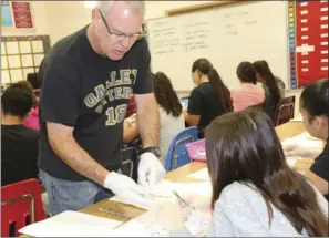  ?? WILLIAM ROLLER PHOTO ?? Tim Dial (left), sixth-grade teacher at Oakley, shows the proper way to remove the fatty tissue from a cow's eyeball.