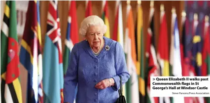  ?? Steve Parsons/Press Associatio­n ?? > Queen Elizabeth II walks past Commonweal­th flags in St George’s Hall at Windsor Castle