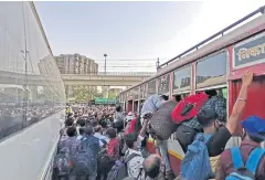  ?? REUTERS ?? People crowd at a bus station to reach their hometown hours before a week-long lockdown ordered by the Delhi government comes to effect on Monday.
