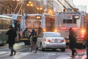  ??  ?? A car turns onto Market Street and is backed up behind a phalanx of buses. “Riding in today I felt more at ease,” said cyclist Juli Uota.