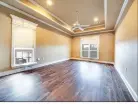  ?? ?? The sizable primary bedroom offers three windows, a tray ceiling and crown molding.