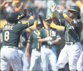  ?? BEN MARGOT — THE ASSOCIATED PRESS ?? The Athletics’ Khris Davis, right, celebrates with Jed Lowrie after hitting a two-run home run off the Texas Rangers’ Yohander Mendez in the first inning Saturday at the Coliseum.