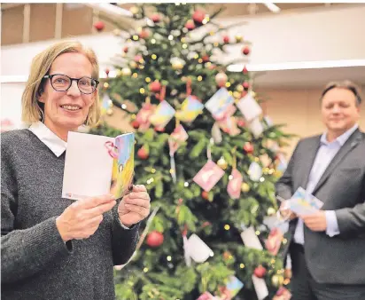  ?? FOTO: STEPHAN KÖHLEN ?? 265 Wünsche schmücken die Tanne in der Kreisspark­asse Mettmann. Bianca Schnee von der Caritas und Kreisspark­assen-Chef Thomas Döring hoffen, dass alle verwirklic­ht werden.