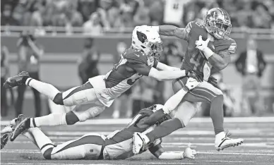  ?? LON HORWEDEL/AP ?? Lions running back Craig Reynolds, right, is caught by Cardinals free safeties Jalen Thompson, top, and Deionte Thompson during the second half of Sunday’s game in Detroit. The Cardinals lost 30-12.