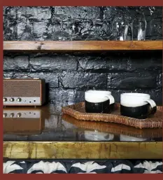  ??  ?? LEFT & BELOW With its black walls and gold details, the kitchen is both glamorous and practical. The shelves are lengths of oak, secured with metal brackets, and the gold-painted worktop (a collaborat­ion between Anna and Daniel Bland) was sealed with layers of poured resin.