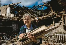  ?? EVGENIY MALOLETKA/AP ?? A woman collects wood for heating from a destroyed school where Russian forces were based in Izium, Ukraine, on Monday.