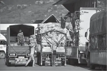  ?? Photo by Redjie Melvic Cawis ?? BUSINESS AS USUAL. Vegetable trading continues at the Benguet Agri-Pinoy Trading Center but workers are urged to use protective equipment such as gloves and facemasks to help prevent the spread of Covid - 19.