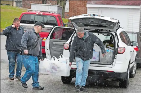  ?? SEAN D. ELLIOT/THE DAY ?? Members of Montville town fire companies, from left, Tom McNally, Oakdale, Jim Sajkowicz, Mohegan, and Raymond Occhialini, Oakdale, carry a tote of food baskets to their car at Montville Social Services on Monday as they head out to distribute them to clients. Firefighte­rs from three town companies, Chesterfie­ld, Oakdale, and Mohegan, distribute­d about 40 food baskets and made two well-being checks on their rounds, according to Chesterfie­ld Public Informatio­n Officer Steven Frischling. The weekly distributi­ons are being made to homes rather than have clients leave their homes.