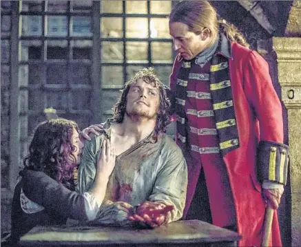  ?? Ed Miller Starz Entertainm­ent ?? “OUTLANDER” stars Caitriona Balfe and Tobias Menzies flank Sam Heughan, whose character, Jamie Fraser, was raped.