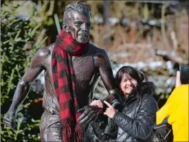  ?? DANA JENSEN/THE DAY ?? Patti Dillon of Windham has her picture taken with the statue of runner Johnny Kelley in downtown Mystic after she placed the scarf around its neck while people gather to participat­e in the 49th annual community run and plunge that ends at Esker Point...