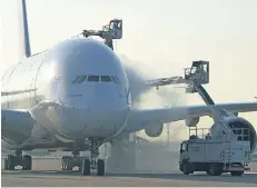  ?? FOTO: DUS ?? Ein Airbus A 380 – das größte Flugzeug der Welt – wird vor dem Start mit Spezialfah­rzeugen enteist.