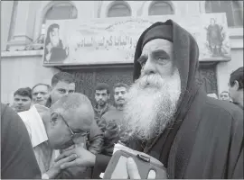  ?? AMR NABIL — THE ASSOCIATED PRESS ?? Priest David, the head of Mar Mina church, is greeted by people outside the church in Helwan, Cairo, Egypt, on Friday where at least nine people have been killed.