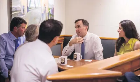  ??  ?? Finance Minister Bill Morneau speaks with small-business owners at a coffee shop in Vancouver on Tuesday.