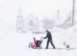  ?? (Jane Tyska/bay Area News Group via AP) ?? J.J. Morgan clears snow on Church Street near the historic Truckee Hotel as snow continues to fall Sunday in downtown Truckee, Calif.