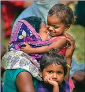 ?? PIC/PTI ?? A migrant woman plays with her child as they wait to board a train to Madhya Pradesh, at Tadepallii in Guntur district, on Monday