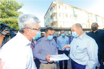  ??  ?? Hajiji receiving the memorandum from a representa­tive of the affected residents during the visit to the Universiti Apartment 1 booster pump station.