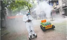  ?? GETTY IMAGES ?? A volunteer operates a robot to disinfect an area amid the COVID-19 outbreak in Wuhan, China, on Monday.