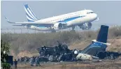  ?? — AFP ?? An airplane takes off at the internatio­nal airport in Kathmandu near the wreckage of a US- Bangla Airlines plane that crashed on Tuesday.