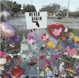  ?? AP PHOTOS ?? ‘DEVASTATED’: Denyse Christian, below, hugs her son Adin Christian, 16, a student at the Marjory Stoneman Douglas High School, at a makeshift memorial, above and below. Nikolas Cruz, charged with killing 17 people at the school in Parkland, Fla.,...