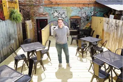  ?? STAFF PHOTO BY C.B. SCHMELTER ?? Bitter Alibi owner Jason Bowers poses in the establishm­ent’s new patio space on Tuesday in Chattanoog­a. Bitter Alibi has expanded into the old Coin-Op space on M.L. King Boulevard.