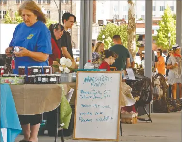  ??  ?? Shopping: Shoppers visit the booths of a variety of vendors while looking for fresh produce and other items to purchase during the grand opening of the MAD Farmers Market Saturday.