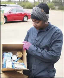  ?? Brodie Johnson • Times-Herald ?? Barbara Curtis, an employee with the City of Forrest City, shows the items included in this month’s box of commoditie­s. The Food Bank of Northeast Arkansas held its monthly distributi­on this morning at the Sports Complex.