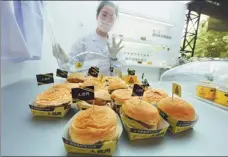  ?? LONG WEI / FOR CHINA DAILY WANG RUIPING / XINHUA ?? Left: A staff member displays burgers made from fake meat in Hangzhou during a shopping festival last year. Right: A customer orders artificial meat at a restaurant in Guangzhou, Guangdong province, in April.