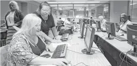  ?? Nati Harnik / Associated Press file ?? Cheryl Bast of Omaha, Neb., left, gets help from daughter Liz Pierson as she applies for a school job. U.S. employers posted slightly fewer openings in October.