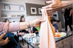  ??  ?? Guests pass around Ruby Ribbon garments during an in-home demonstrat­ion and sales party in Noe Valley for the apparel company’s line.