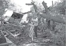  ?? L. TODD SPENCER/THE VIRGINIAN-PILOT VIA AP ?? Dave Stough recovers a flag Friday that had been attached to his carport that was crushed by a large tree crashing onto his mobile home, in Virginia Beach, Va.