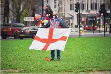  ?? ALBERTO PEZZALI/ASSOCIATED PRESS ?? A man holds an English flag in London’s Parliament Square on Dec. 31. Britain’s formal departure from the EU becomes a fact of daily life today as the UK leaves the world’s most powerful trading bloc.